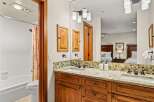 This bathroom features a double sink vanity with granite countertops and warm wood cabinetry.