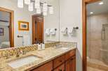 This bathroom boasts a double vanity with granite countertops and mosaic tile backsplash, providing both style and functionality.