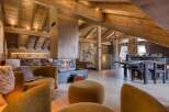 Discover a luxurious chalet interior featuring exposed wooden beams, a modern fireplace, and stylish, comfortable seating.