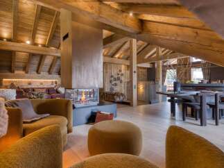 Discover a luxurious chalet interior featuring exposed wooden beams, a modern fireplace, and stylish, comfortable seating.