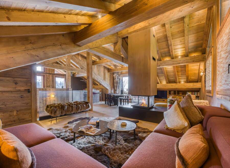 Luxury chalet interior featuring a cozy living area with a modern fireplace, plush seating, and rustic wooden beams, perfect for a ski vacation.