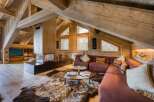 Discover this luxurious chalet featuring exposed wooden beams, a modern fireplace, and cozy sectional seating.