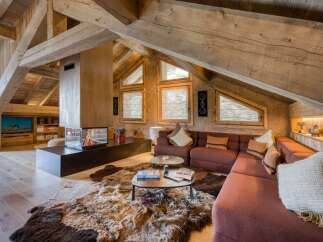 Discover this luxurious chalet featuring exposed wooden beams, a modern fireplace, and cozy sectional seating.