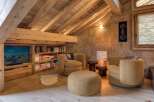 This inviting attic space is designed as a cozy retreat, featuring exposed wooden beams and built-in wooden shelving.