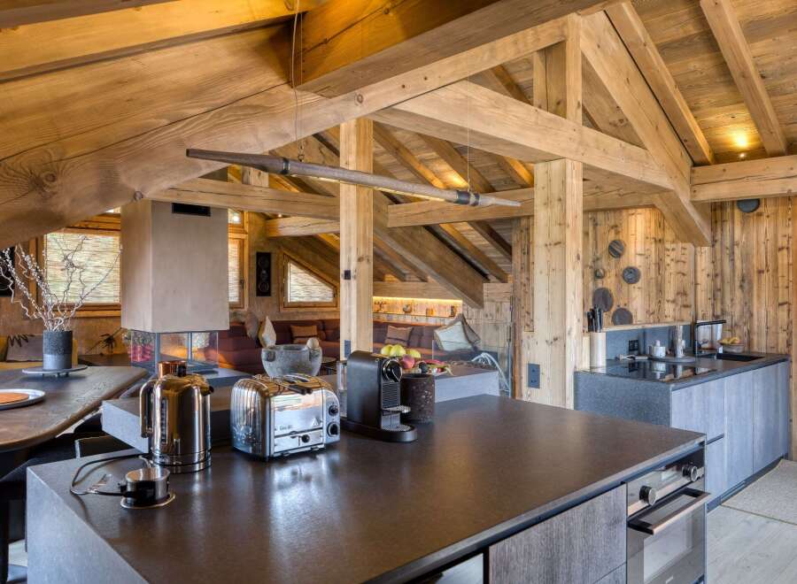 Discover this luxurious chalet featuring a modern kitchen with sleek countertops, high-end appliances, and rustic wooden beams.