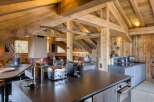 Discover this luxurious chalet featuring a modern kitchen with sleek countertops, high-end appliances, and rustic wooden beams.