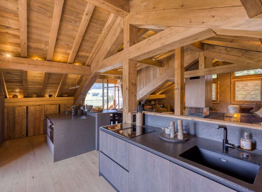 Discover a stunning chalet kitchen with exposed wooden beams, offering a rustic yet modern ambiance.