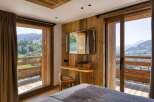 Experience mountain living in this charming bedroom featuring wood paneling, a built-in desk, and a private balcony.