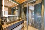 This bathroom features a stunning stone sink and shower with matching stone walls, complemented by warm wood accents on the ceiling and vanity.