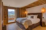 Experience luxury in this mountain view bedroom featuring warm wood accents and modern lighting.