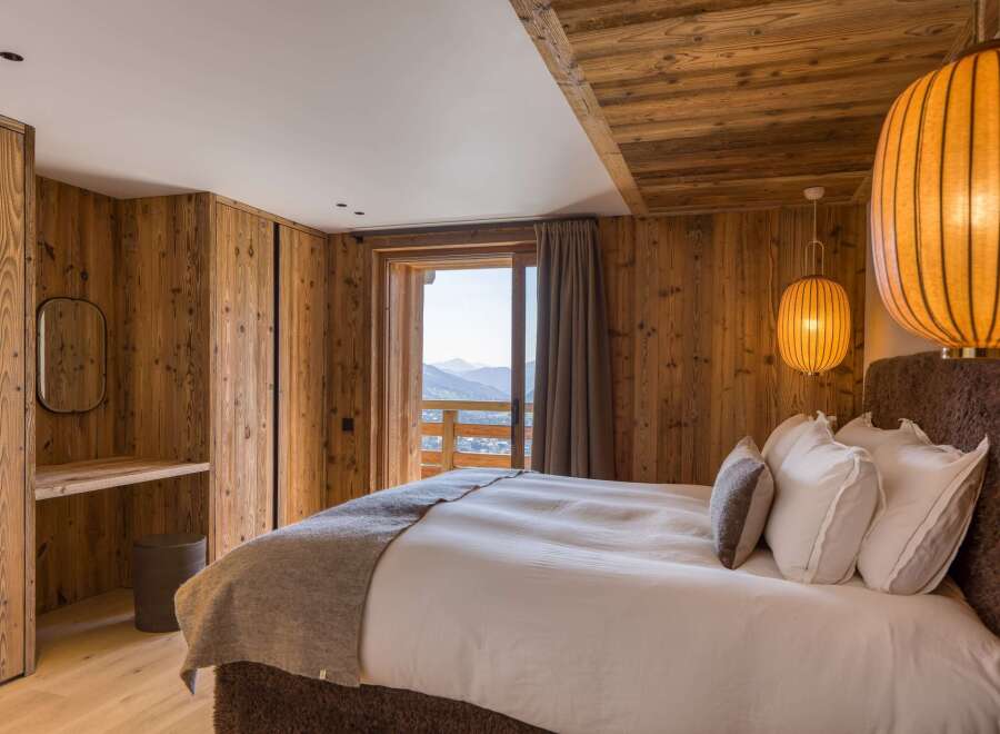 Experience luxurious mountain living in this bedroom with rustic wood finishes and stunning mountain views.