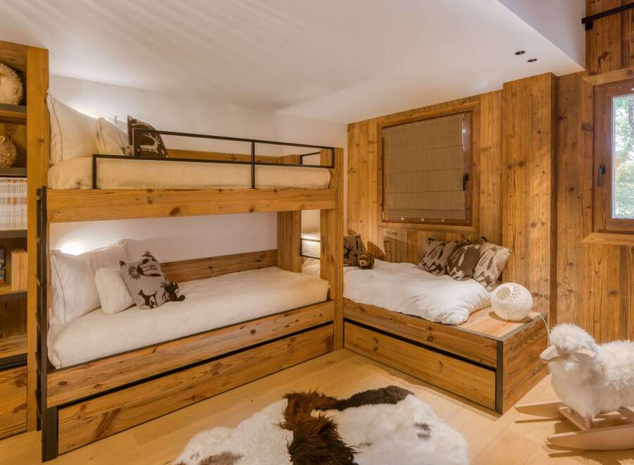 This cozy bedroom features custom-built wooden bunk beds and a charming twin bed nook, perfect for a mountain retreat.