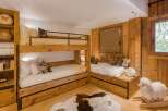 This cozy bedroom features custom-built wooden bunk beds and a charming twin bed nook, perfect for a mountain retreat.