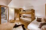 This cozy bedroom features a unique bunk bed design, maximizing space while adding rustic charm.