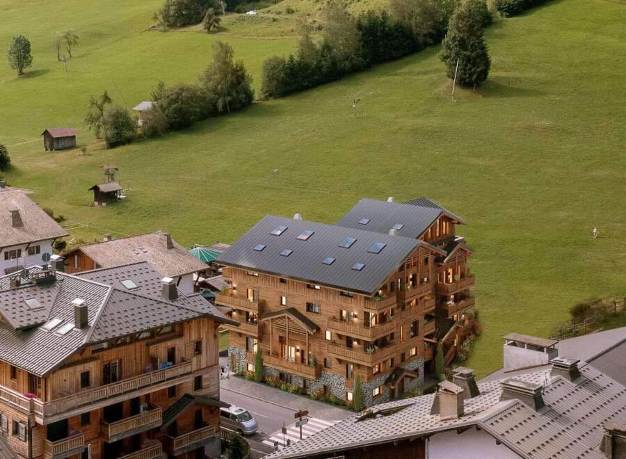 Luxury chalet-style apartment building nestled in a picturesque mountain village, offering stunning views and a peaceful retreat.