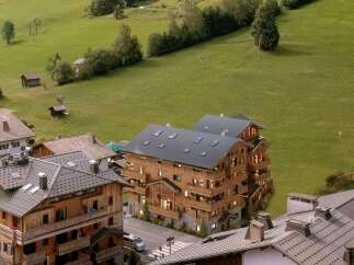 Luxury chalet-style apartment building nestled in a picturesque mountain village, offering stunning views and a peaceful retreat.