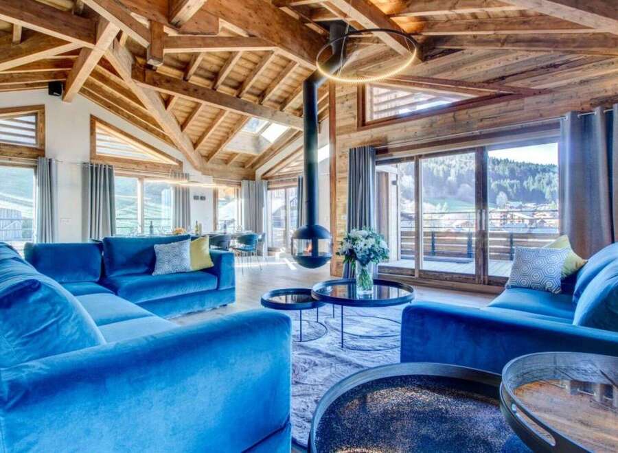 This luxurious chalet features a spacious living area with high ceilings, exposed wooden beams, and a modern fireplace.