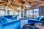 This luxurious chalet features a spacious living area with high ceilings, exposed wooden beams, and a modern fireplace.