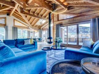 This luxurious chalet features a spacious living area with high ceilings, exposed wooden beams, and a modern fireplace.