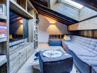 Discover this cozy attic space, featuring a custom wood entertainment center with built-in shelving and storage.