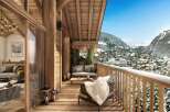 A luxurious chalet balcony offers stunning mountain views, inviting seating, and rustic wooden architecture.