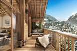 A luxurious chalet balcony offers stunning mountain views, inviting seating, and rustic wooden architecture.