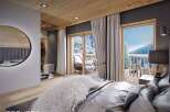 This luxurious bedroom boasts a private balcony with stunning mountain views, perfect for a serene retreat.