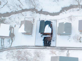A snowy aerial view captures several homes nestled in a serene, possibly rural or suburban setting, complete with snow-covered rooftops and yards.
