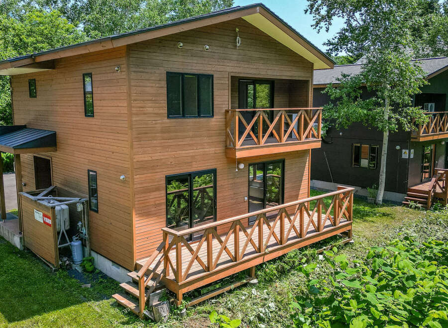 This charming wooden house features a spacious deck, perfect for enjoying the surrounding greenery.