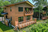 This charming wooden house features a spacious deck, perfect for enjoying the surrounding greenery.
