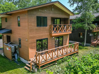 This charming wooden house features a spacious deck, perfect for enjoying the surrounding greenery.