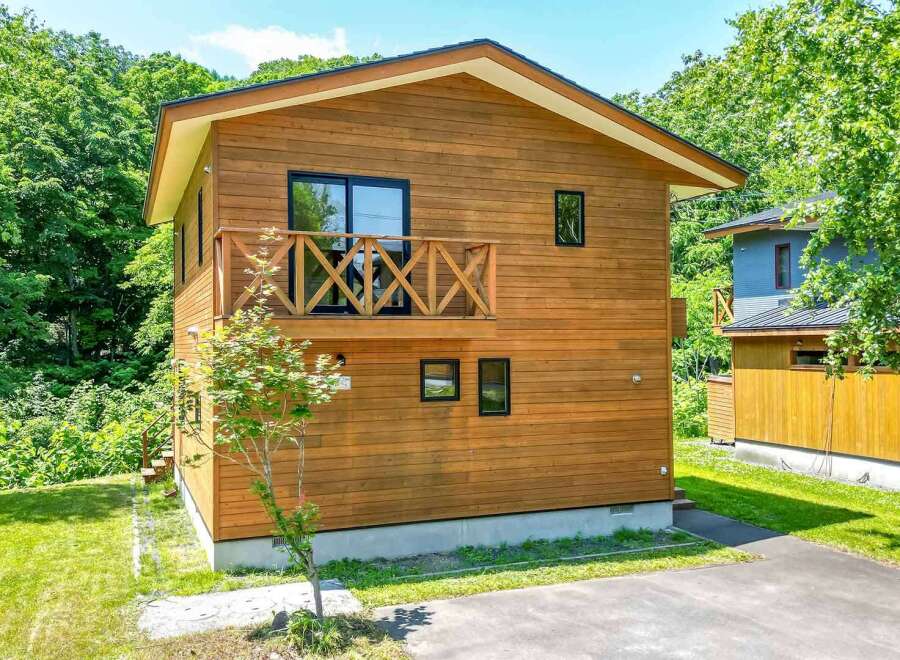 This beautiful two-story house features a natural wood exterior and a charming balcony.