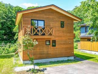 This beautiful two-story house features a natural wood exterior and a charming balcony.