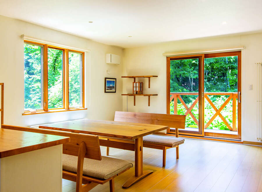 This inviting dining area features large windows offering serene forest views, perfect for nature lovers.