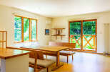 This inviting dining area features large windows offering serene forest views, perfect for nature lovers.