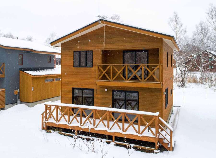 This beautiful two-story wood house features a charming balcony and a spacious deck, perfect for enjoying the snowy scenery.