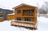 This beautiful two-story wood house features a charming balcony and a spacious deck, perfect for enjoying the snowy scenery.
