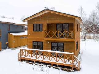 This beautiful two-story wood house features a charming balcony and a spacious deck, perfect for enjoying the snowy scenery.