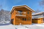 Discover this charming wooden house nestled in a serene, snow-covered landscape.