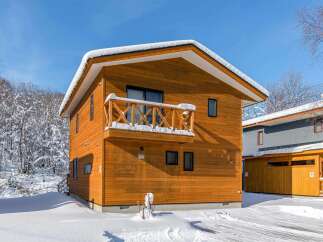 Discover this charming wooden house nestled in a serene, snow-covered landscape.