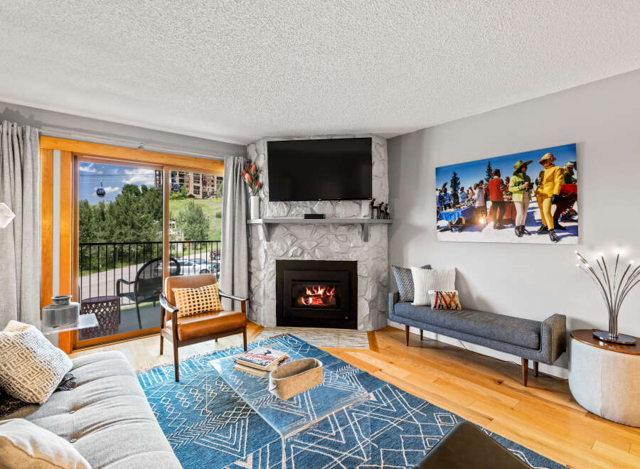 This cozy living room features a stone fireplace with a mounted TV, creating a warm focal point.