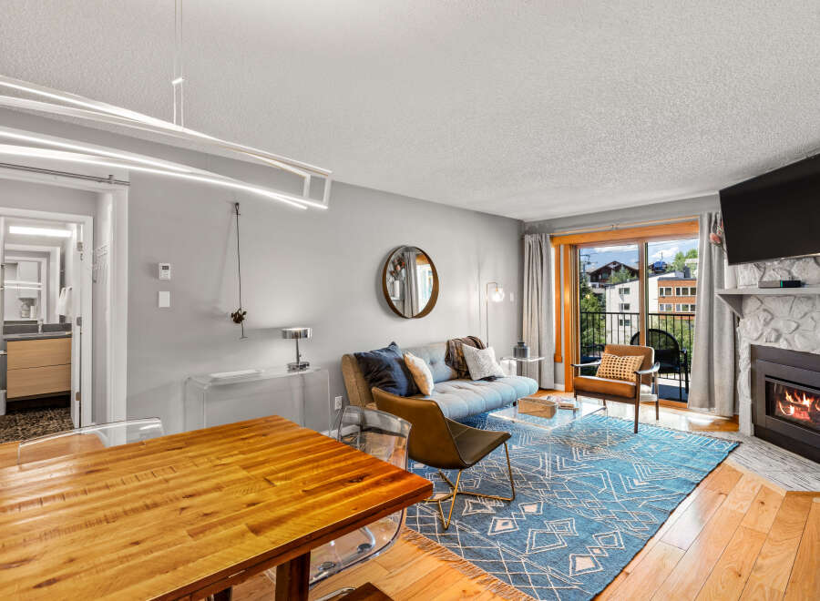 Step into this inviting condo featuring a cozy living space with a stone fireplace and a balcony offering scenic views.