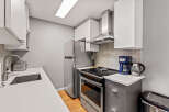 This modern kitchen features sleek white cabinets, stainless steel appliances, and a stylish geometric backsplash.
