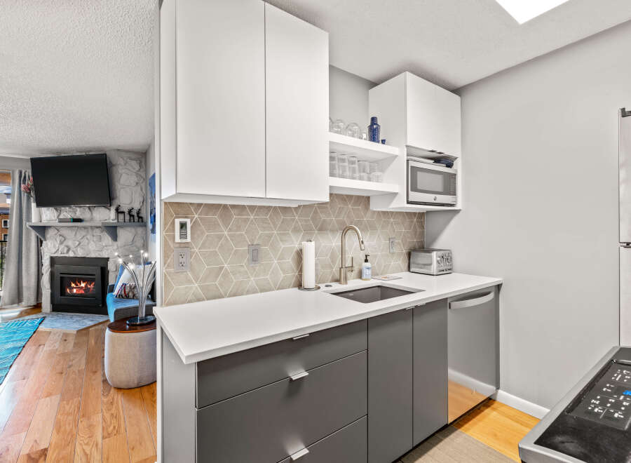 This cozy condo features a modern kitchen with white countertops, sleek gray cabinetry, and stainless steel appliances.