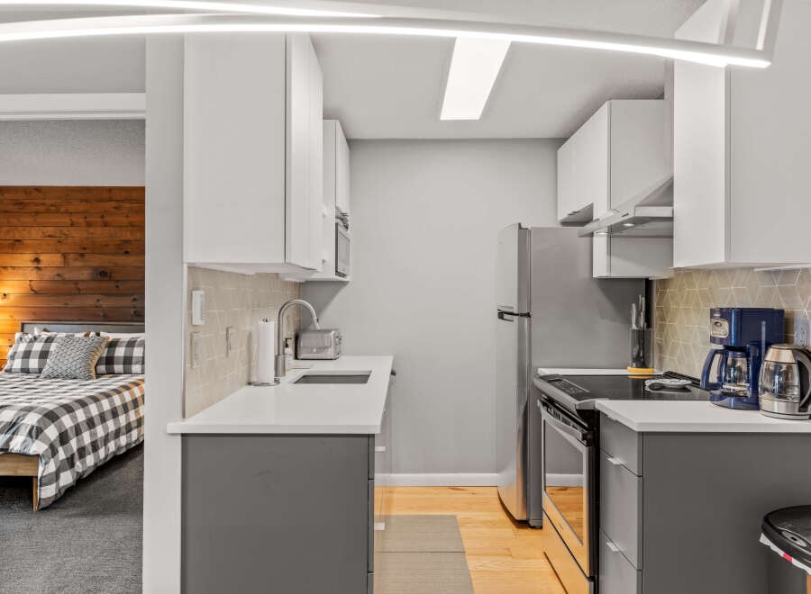 This compact kitchen boasts modern design with its sleek white cabinets and contrasting gray lower cabinets.