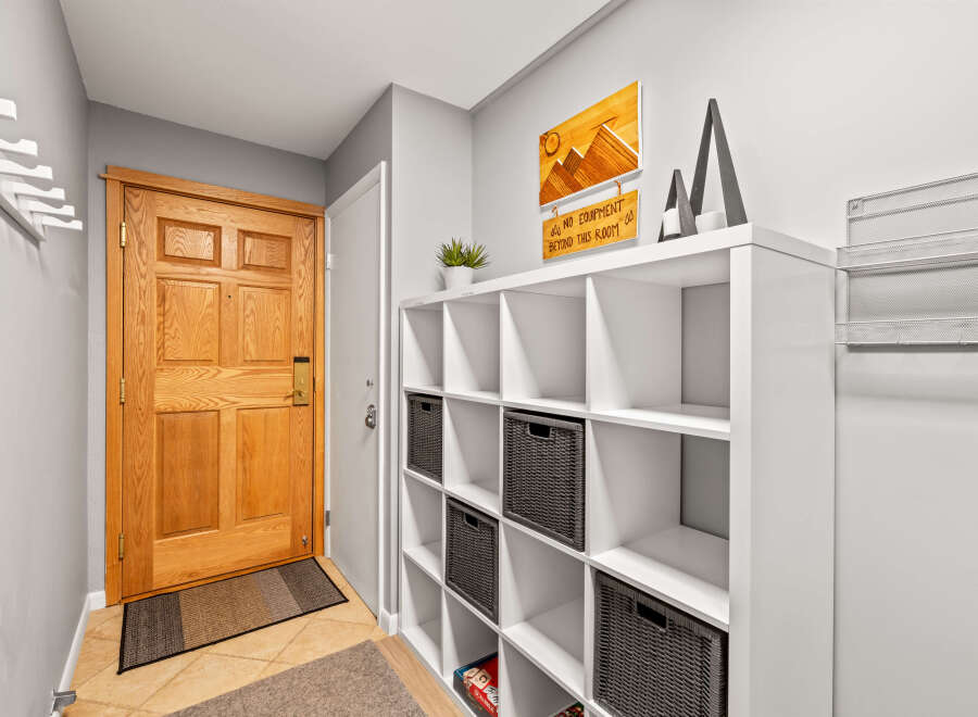 A welcoming entryway features a beautiful wood door, a functional storage unit with woven baskets, and stylish wall decor.