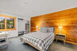 Discover a cozy bedroom featuring a striking wood-paneled wall, a comfortable bed with a stylish gray and white checkered duvet, and functional built-in closet space.