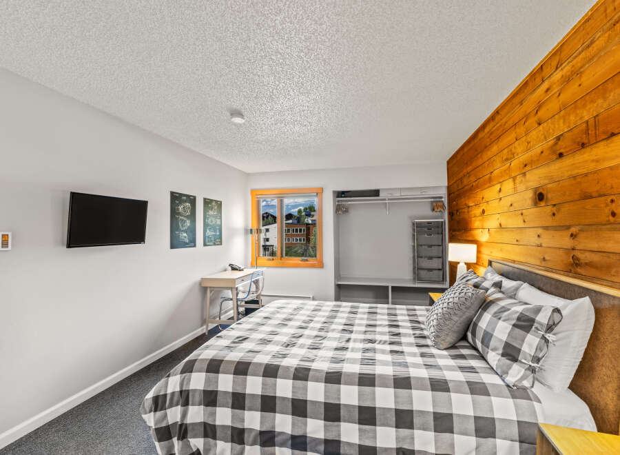 This bedroom features a unique wood accent wall, adding warmth and character to the space.