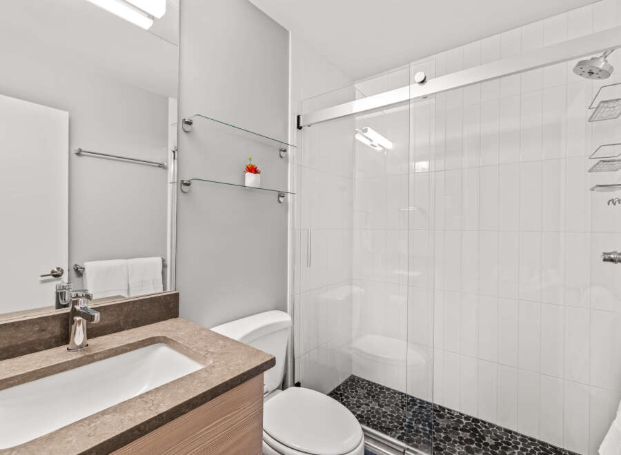 This modern bathroom features a sleek vanity with a brown countertop and wooden cabinet.