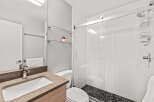 This modern bathroom features a sleek vanity with a brown countertop and wooden cabinet.